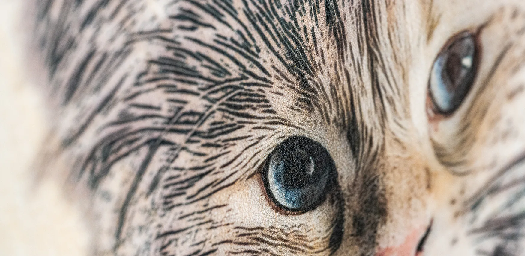 Extreme close-up of a wood burn style cat portrait, showing the fine lines of the fur and the blue eye in detail against the texture of the wood.